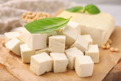 Delicious tofu cheese, basil and soybeans on wooden board, closeup