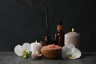 Photo of Beautiful composition with burning candles and different spa products on dark grey table