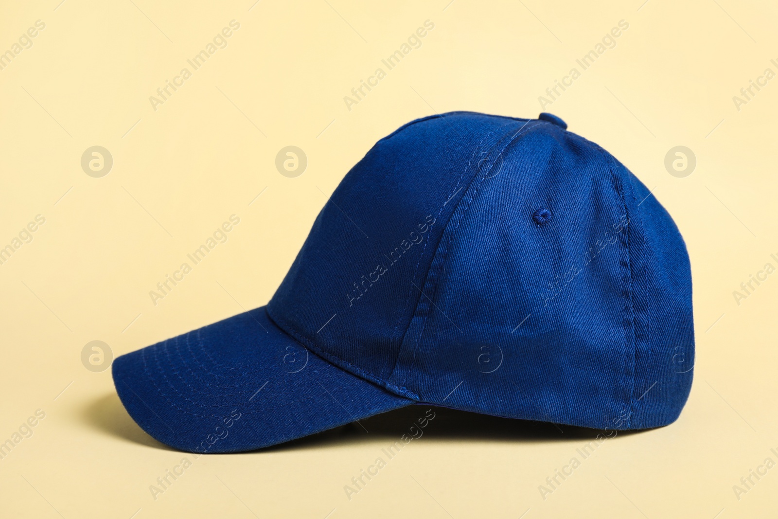 Photo of Stylish blue baseball cap on beige background