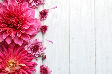 Photo of Flat lay composition with beautiful dahlia flowers and space for text on wooden background