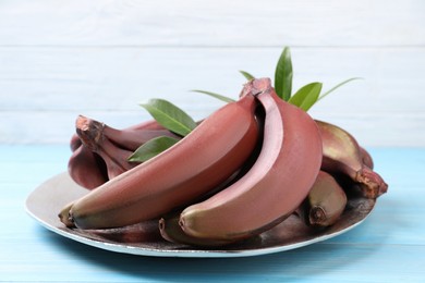 Photo of Tasty red baby bananas on light blue wooden table