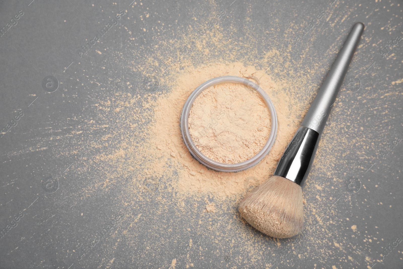 Photo of Loose face powder and makeup brush on grey background, flat lay