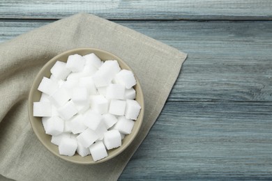 White sugar cubes in bowl on wooden table, top view. Space for text