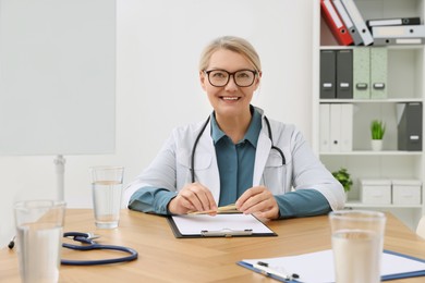 Photo of Professional doctor sitting at wooden table in clinic