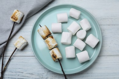 Photo of Fresh and roasted marshmallows on white wooden table, flat lay
