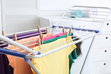 Clean laundry hanging on drying rack indoors, closeup