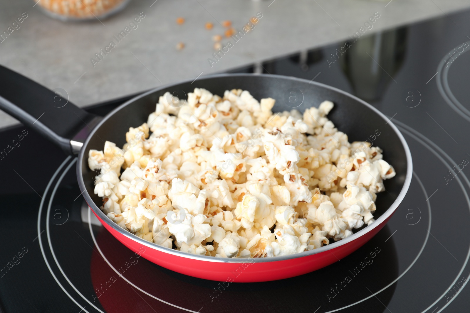 Photo of Frying pan with tasty popcorn on stove in kitchen