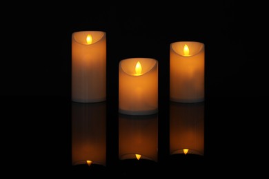 Photo of Glowing decorative LED candles on black background