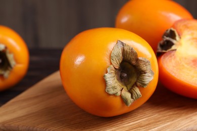 Whole and cut delicious ripe persimmons on wooden table, closeup