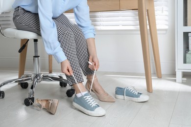 Photo of Woman changing shoes at workplace in office, closeup