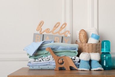 Photo of Baby clothes, toy and accessories on wooden table