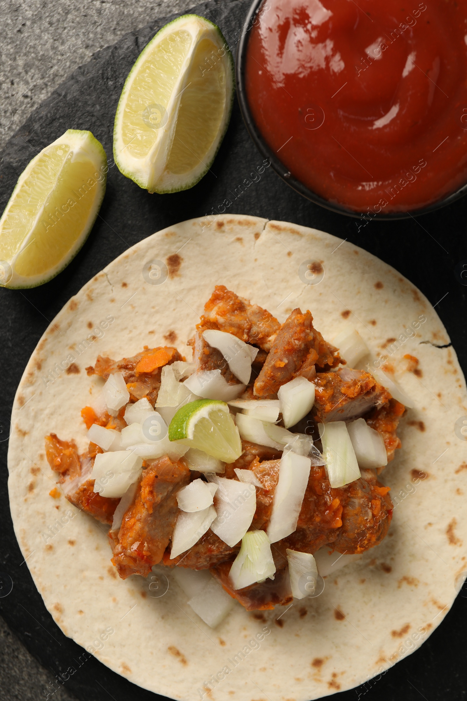 Photo of Delicious taco with vegetables, meat and ketchup on grey table, top view