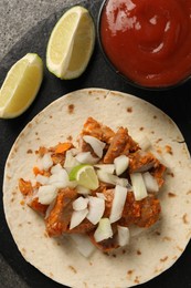 Photo of Delicious taco with vegetables, meat and ketchup on grey table, top view