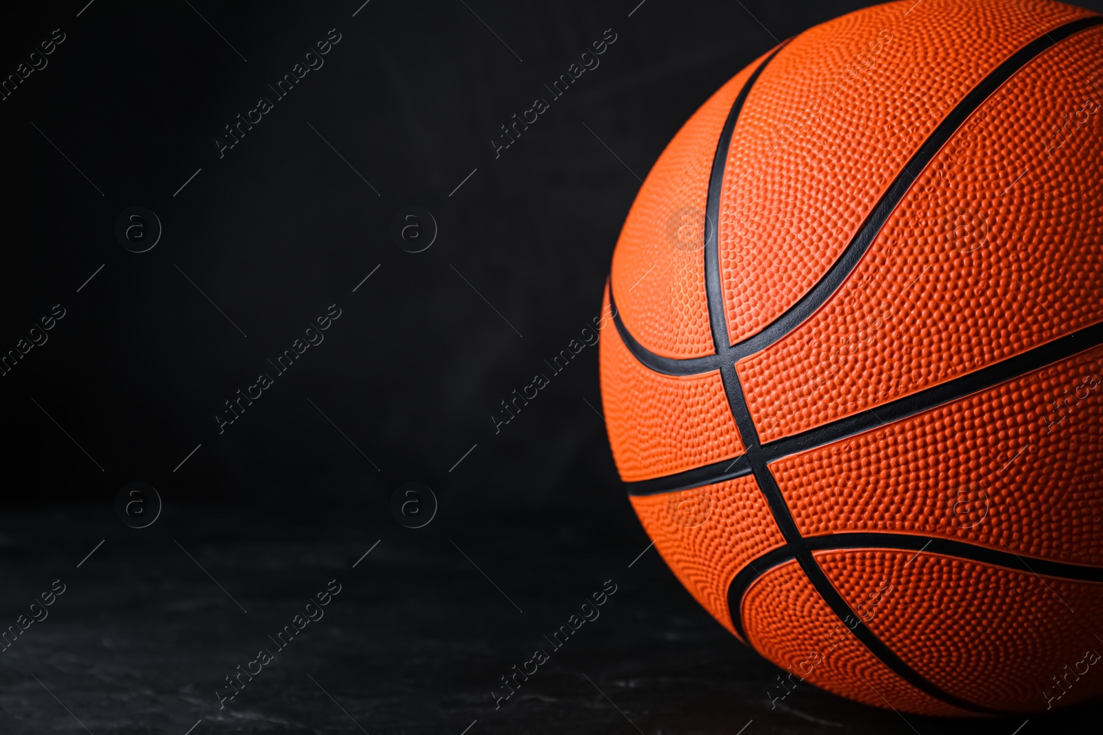 Photo of Orange ball on black background, space for text. Basketball equipment