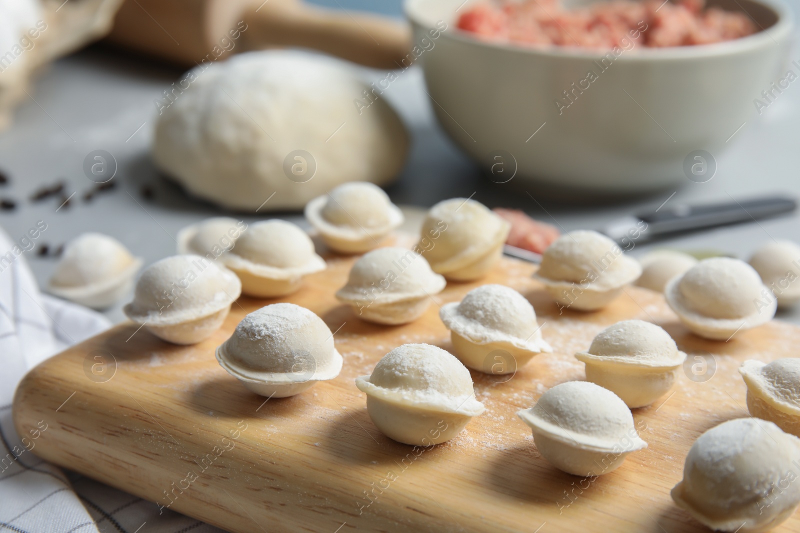 Photo of Board with raw dumplings on table, closeup. Process of cooking