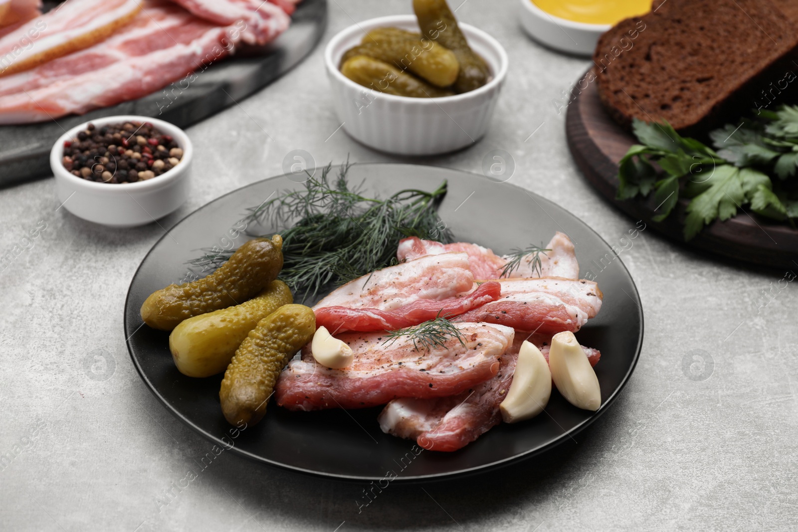 Photo of Tasty pork fatback, pickled cucumbers and ingredients on grey table