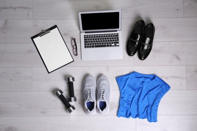 Photo of Flat lay composition of business items with sport accessories on white wooden background. Life and work balance concept