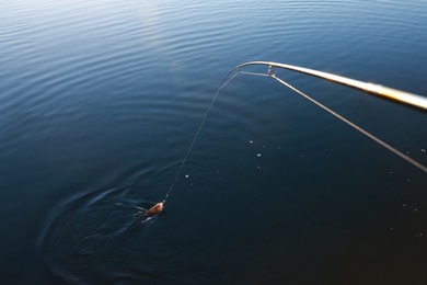 Photo of Fishing rod with catch at riverside on sunny day