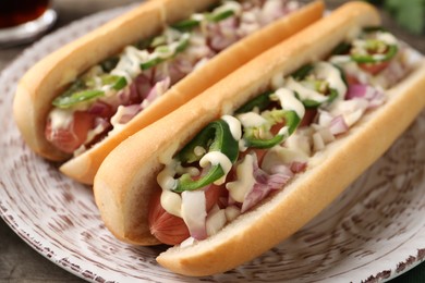 Photo of Delicious hot dogs with onion, chili pepper and sauce on table, closeup
