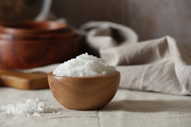 Photo of Organic salt in wooden bowl on table, closeup