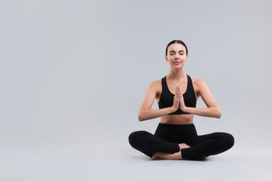 Photo of Beautiful young woman practicing yoga on grey background, space for text. Lotus pose