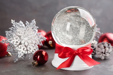 Photo of Beautiful Christmas snow globe and festive decor on grey table