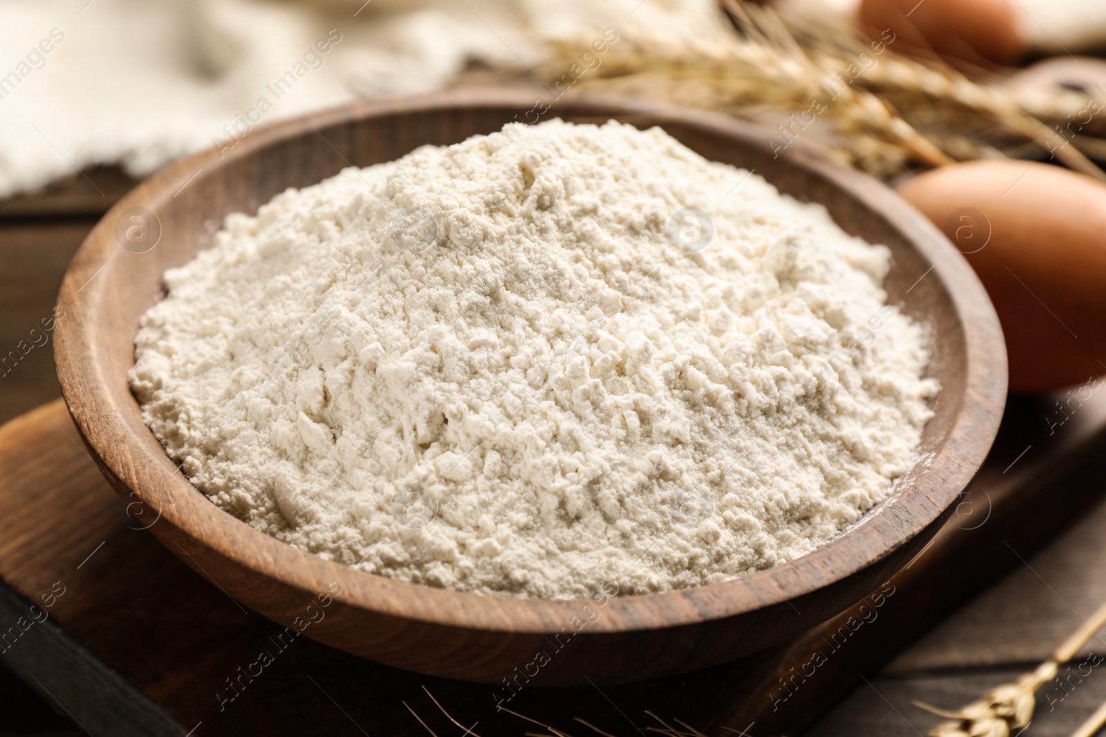 Photo of Bowl with wheat flour on wooden table, closeup