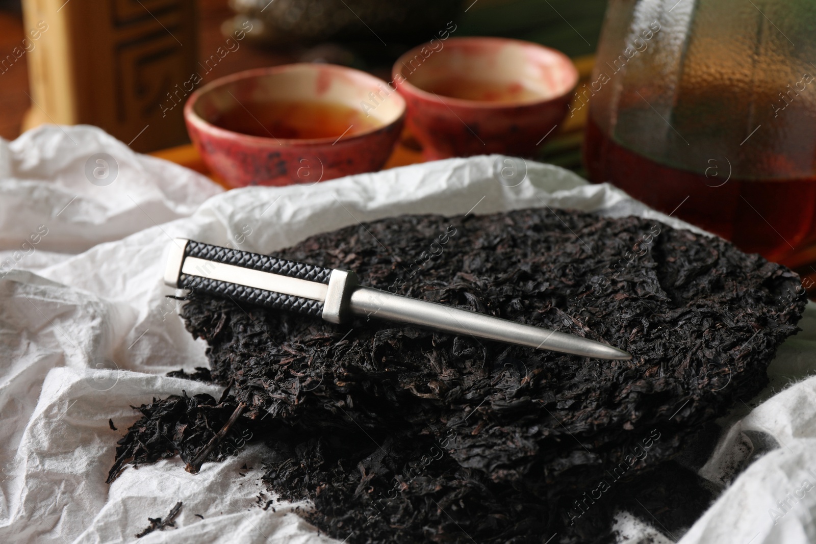 Photo of Broken disc shaped pu-erh tea and knife on parchment paper