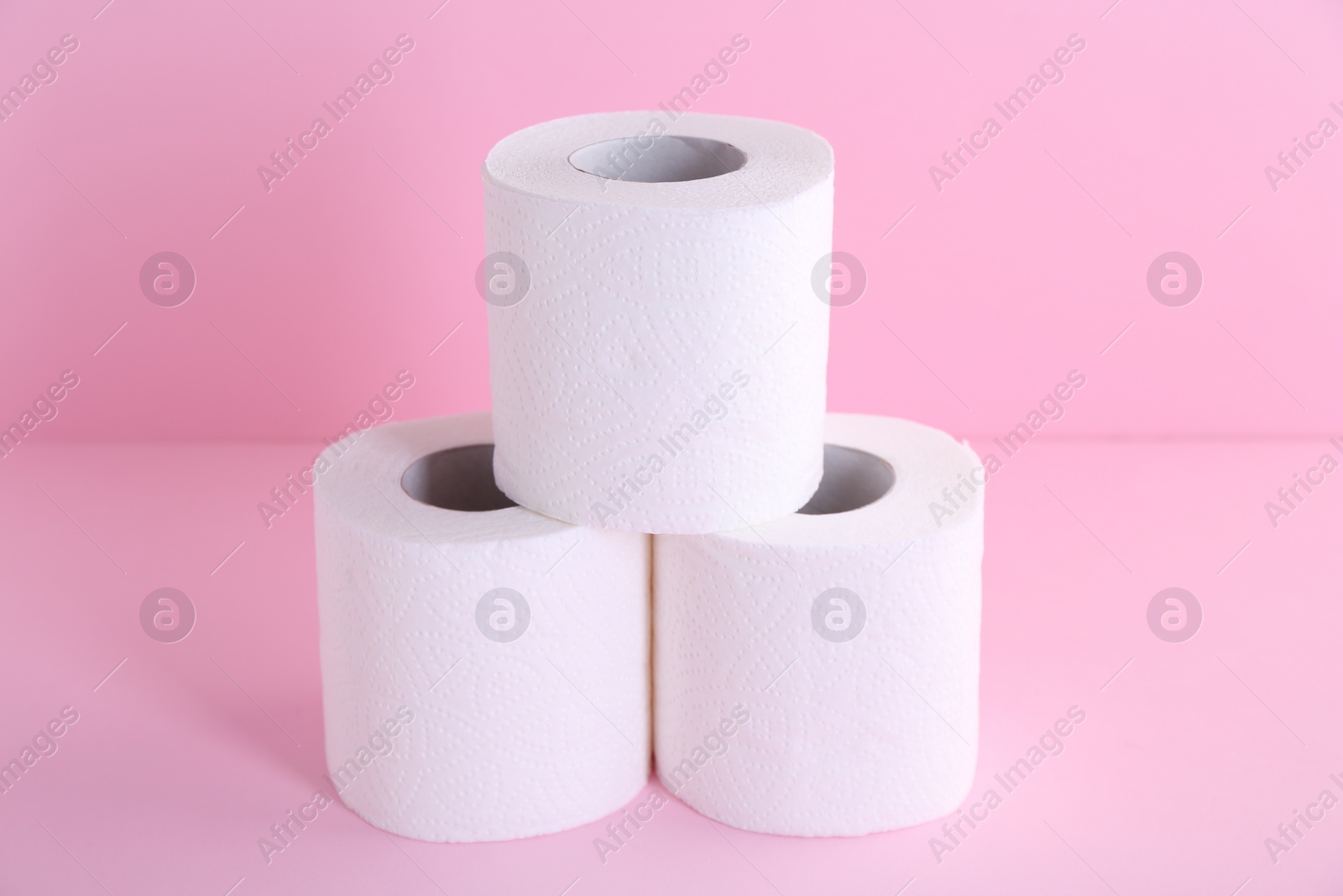 Photo of Soft toilet paper rolls on pink background, closeup