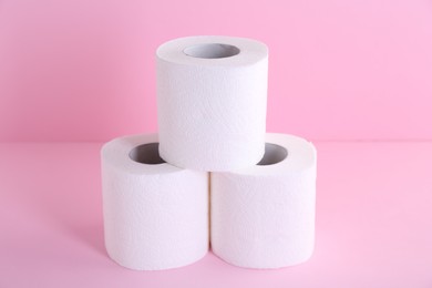 Photo of Soft toilet paper rolls on pink background, closeup