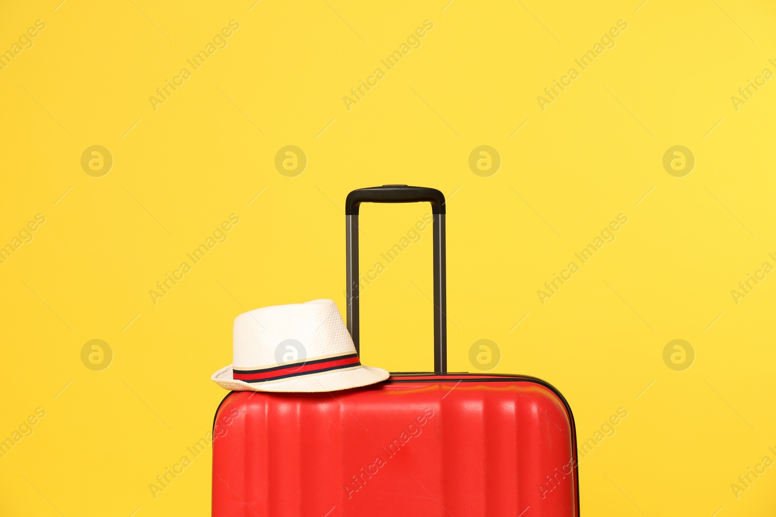 Photo of Bright suitcase with hat on color background