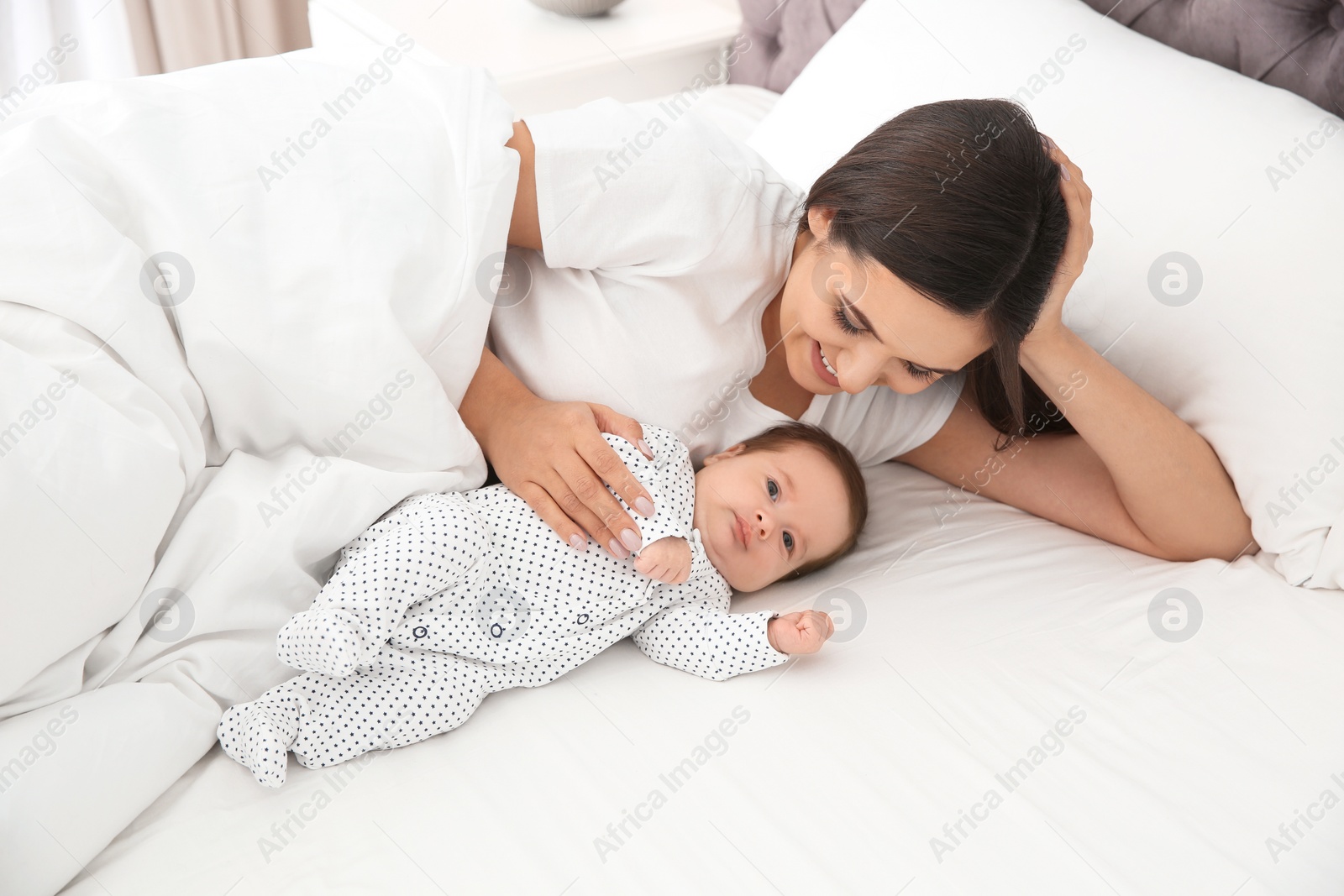 Photo of Happy woman with her cute baby on bed