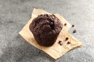 Photo of Delicious chocolate muffin on grey textured table, closeup