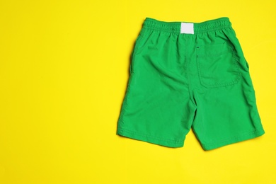 Photo of Stylish male swim trunks on color background, top view with space for text. Beach object