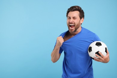 Photo of Emotional sports fan with soccer ball on light blue background, space for text