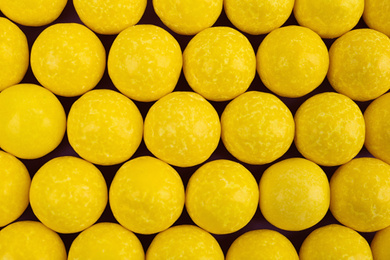 Delicious lemon chewing gums as background, top view