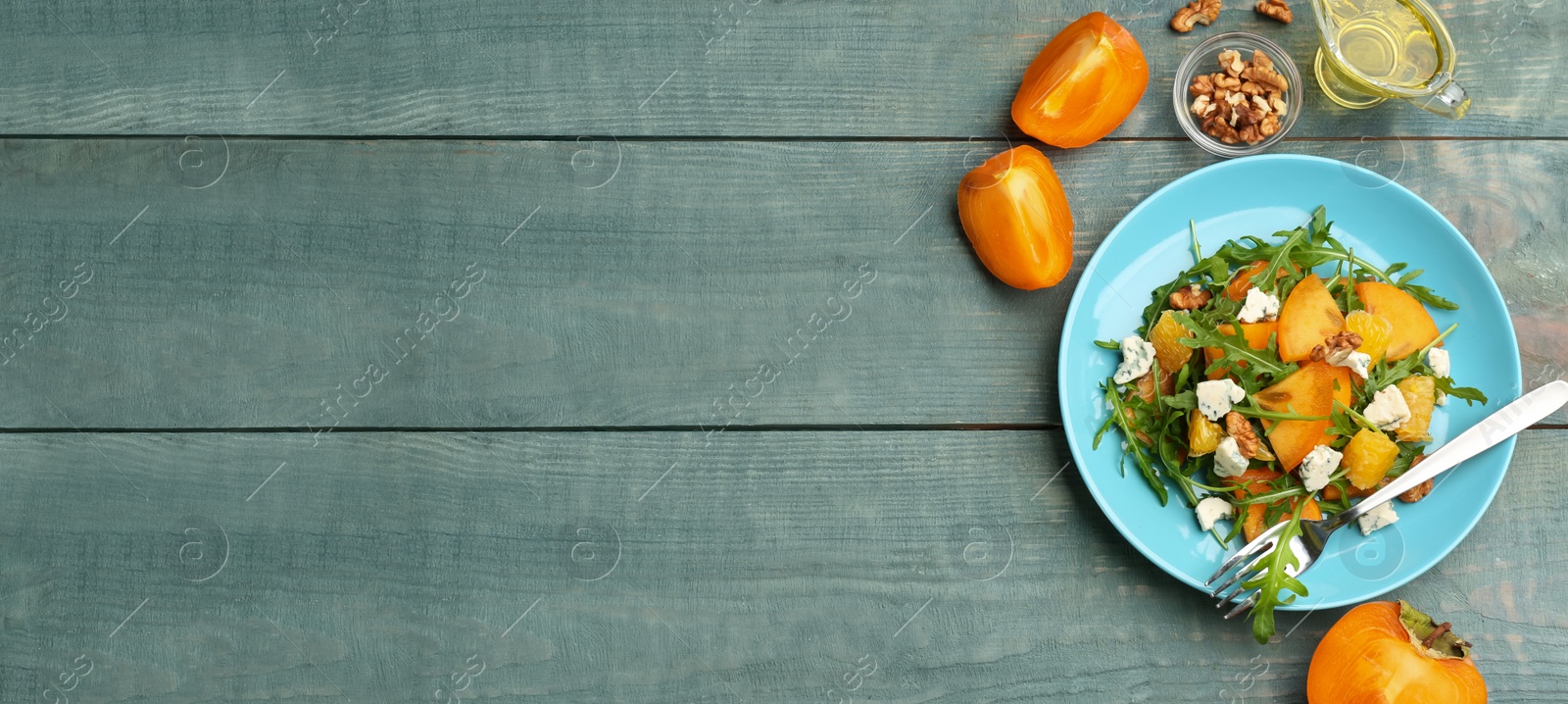 Image of Delicious persimmon salad served on light blue wooden table, flat lay with space for text. Banner design