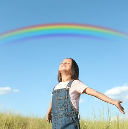 Image of Beautiful rainbow in blue sky over cute little girl in field on sunny day