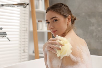 Photo of Woman taking bath with shower gel in bathroom, space for text
