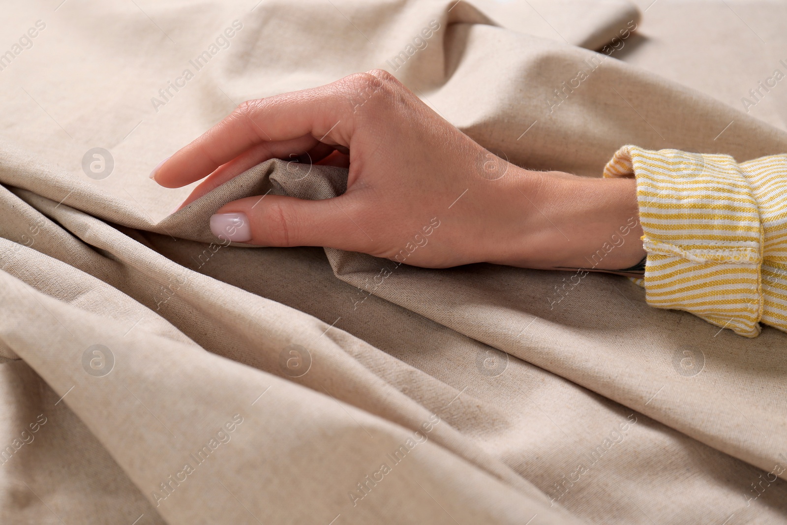 Photo of Woman touching soft beige fabric, closeup view