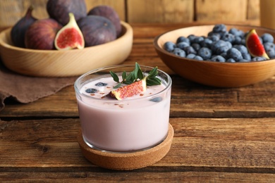 Delicious fig smoothie in glass on wooden table