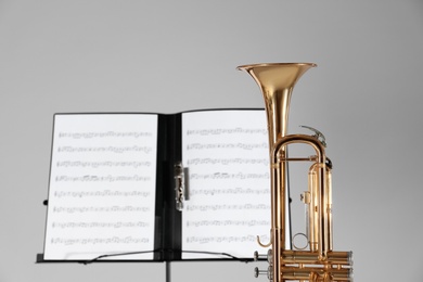 Photo of Trumpet and note stand with music sheets on grey background