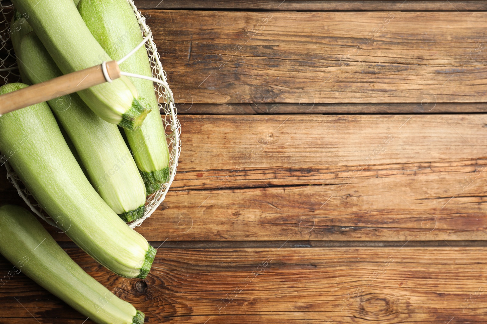 Photo of Basket with ripe zucchinis on wooden table, flat lay. Space for text