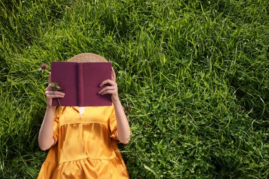 Photo of Woman reading book on green meadow, above view