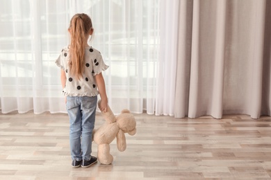 Photo of Lonely little girl with toy indoors. Autism concept