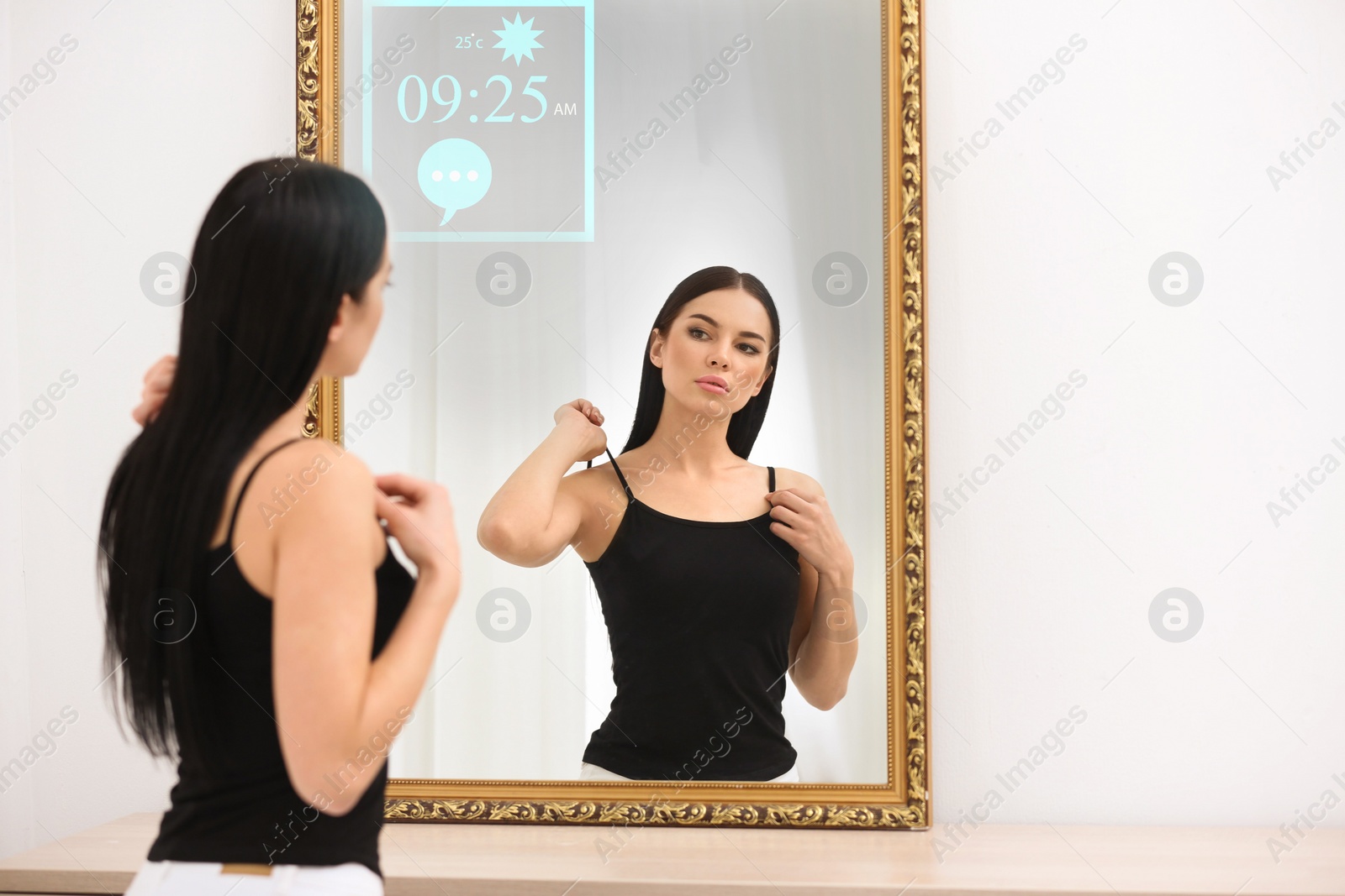 Image of Beautiful young woman looking at herself in smart mirror indoors