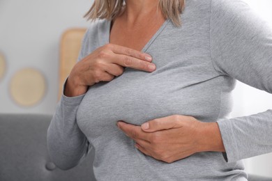 Photo of Woman doing breast self-examination at home, closeup