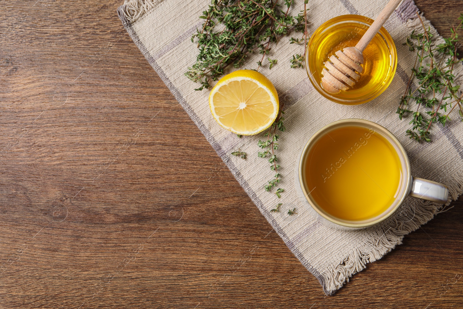 Photo of Aromatic herbal tea with thyme, honey and lemon on wooden table, top view. Space for text