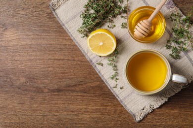 Aromatic herbal tea with thyme, honey and lemon on wooden table, top view. Space for text