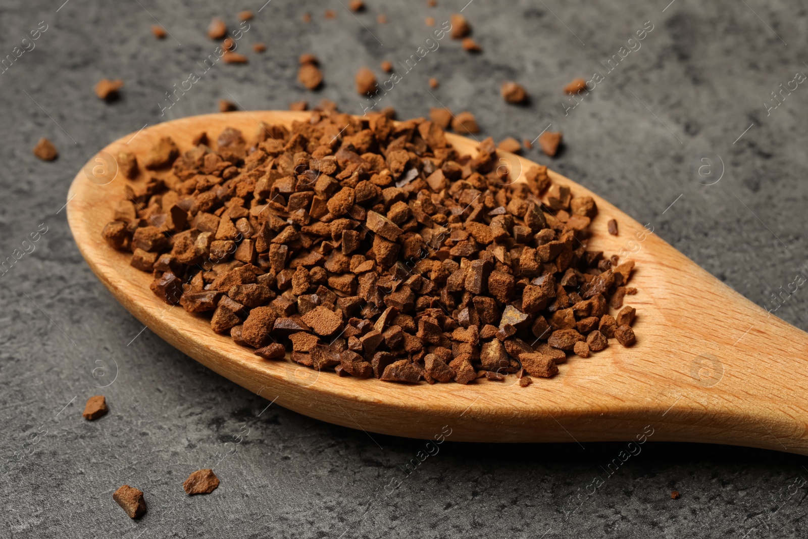 Photo of Spoon of chicory granules on grey table, closeup